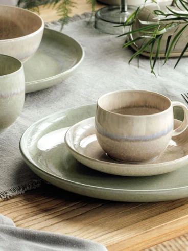 Une décoration de table rustique avec des assiettes et des tasses Perlemor dans des tons terreux discrets sur une table en bois.