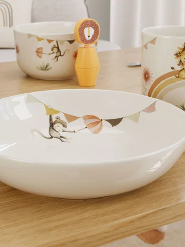 Assiette et tasse de la collection Boho Kids - Roar like a Lion Assiette et tasse de la collection Boho Kids - Roar like a Lion de Villeroy & Boch, avec des motifs d'animaux colorés et des décorations sur une table en bois.