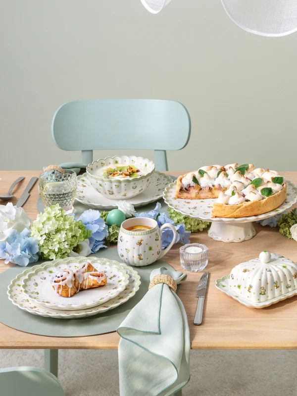 Une table dressée pour quatre personnes sur le thème Easter Delight avec des décorations Easter Delight, de la vaisselle aux couleurs pastel et des assiettes soigneusement disposées.