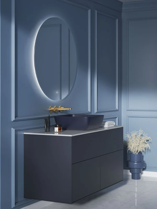 Lavabo Artis bleu dans une salle de bains bleue Une salle de bains moderne avec des murs revêtus de bleu, un grand miroir ovale, un meuble vasque foncé et un vase avec des fleurs blanches posé au sol.