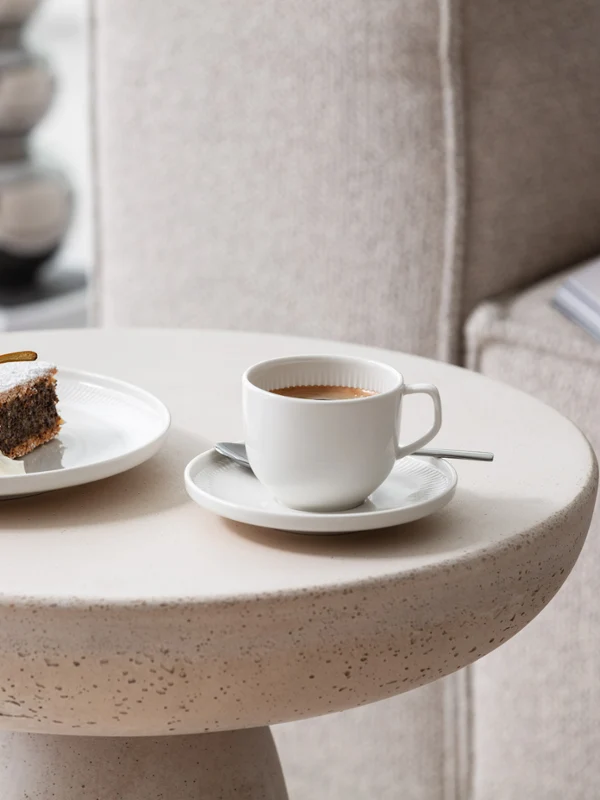 Une tasse et une assiette Afina avec du gâteau et du café Une tasse à café et une assiette avec du gâteau sur une table d’appoint moderne et avec de la vaisselle Afina de Villeroy & Boch.