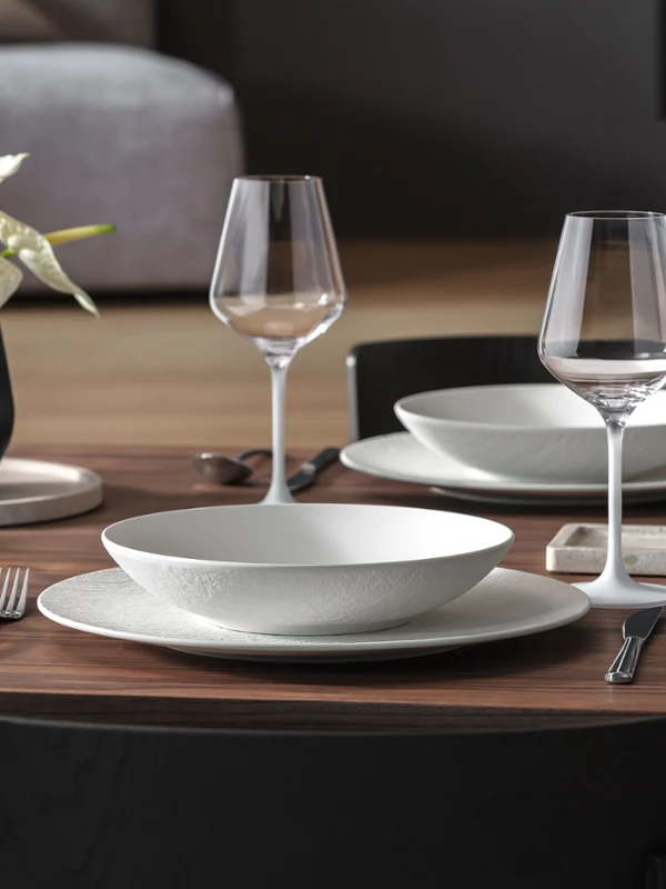 Un ensemble soigné comprenant Manufacture Rock, vase Collier, Travertine, lanterne Noir et bougeoir, dans une élégante mise en table moderne.
