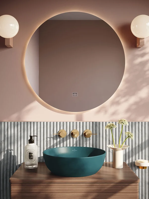 Lavabo Artis Teal avec robinetterie dorée Salle de bains moderne avec un miroir rond, deux lampes sphériques, un lavabo bleu, un mur à rayures et un plan de travail en bois avec des détails décoratifs.