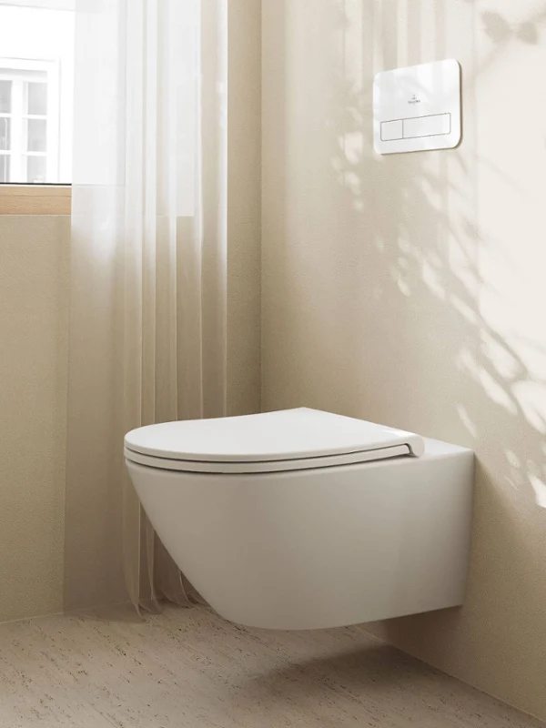 Une salle de bains entièrement noire avec baignoire Une salle de bains minimaliste avec une baignoire murale Collaro noire, des murs sombres, deux appliques murales rondes et une serviette verte. L’ombre et une petite plante donnent de la structure à la scène.