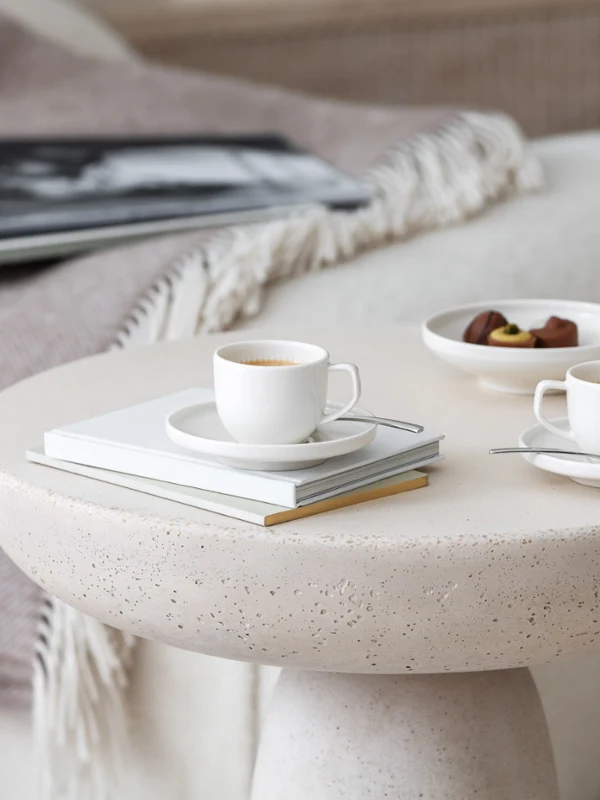 Des tasses à expresso Afina avec des chocolats sur une table basse Deux élégantes tasses à expresso Afina sur une table ronde avec un magazine et une assiette de chocolats.