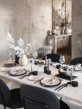 De la vaisselle, des couverts de table, un verre, un vase Manufacture sur une table en pierre naturelle Une grande table en pierre naturelle, dressée avec de la vaisselle, des verres et des couverts de table Manufacture Rock et avec un vase Manufacture Collier.