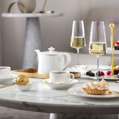 L’heure du thé à l’anglaise avec de la vaisselle Château Septfontaines et des verres MetroChic Une composition de table élégante pour le thé de l’après-midi avec des desserts et du champagne sur une table en marbre, servis sur de la vaisselle Château Septfontaines et avec des verres MetroChic.