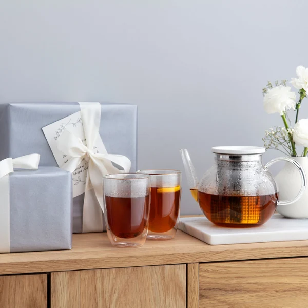 Deux tasses à thé Artesano et une théière sur une table en bois Deux tasses à thé Artesano et une théière sur une table en bois, accompagnées d’un vase avec des fleurs blanches.