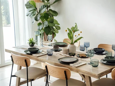 Table à manger pour six avec assiettes Lave de Villeroy & Boch Table à manger dressée pour six personnes avec des assiettes de la collection Lave de Villeroy & Boch, verres et plantes en centre de table dans une pièce lumineuse.