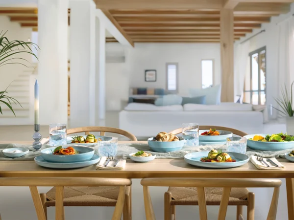 Une table à manger en bois pour quatre personnes avec des assiettes bleues nacrées Aqua dans un salon lumineux et moderne.
