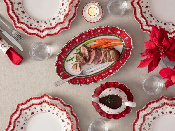 Toy's Delight meat fork Décoration de table festive avec des assiettes rouges et blanches, un rôti, des carottes, une saucière et un poinsettia rouge en guise de centre de table.