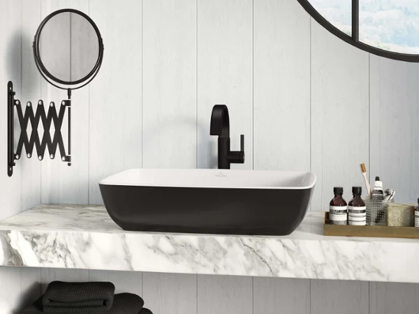 Un intérieur de salle de bains moderne avec une vasque à poser rectangulaire noire Artis installée sur un plan en marbre, un robinet noir et un miroir fixé au mur.