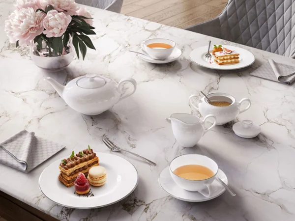 Un service à thé Anmut élégant et gracieux sur une table en marbre Un élégant service à thé Anmut sur une table en marbre, composé d’une théière, de tasses et d’un pot à lait avec du thé et des biscuits.