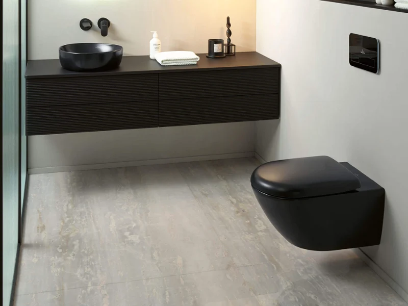 Des toilettes Antao noires dans une salle de bains moderne au look noir et blanc Une salle de bains avec des toilettes noires ainsi qu’un lavabo de la collection Antao dans une pièce moderne au look noir et blanc.