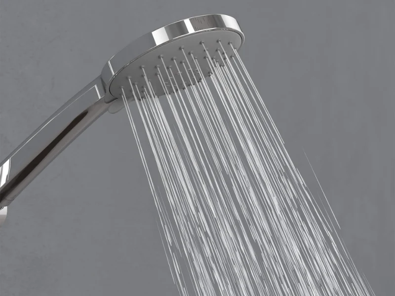 Douchette Universal Showers en mode Relax Un pommeau de douche chromé diffusant des jets d’eau vers le bas devant un simple fond gris.