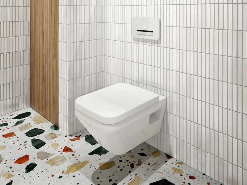 Une salle de bains avec des murs carrelés en blanc, des WC suspendus Architectura, une niche recouverte de bois avec des articles de toilette et un sol en terrazzo avec des fragments colorés.