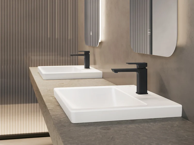 Lavabo Subway 3.0 avec robinetterie noire de Villeroy & Boch Une salle de bains moderne et minimaliste avec des murs beiges, des robinetteries noires et un plan double sous des miroirs rectangulaires.