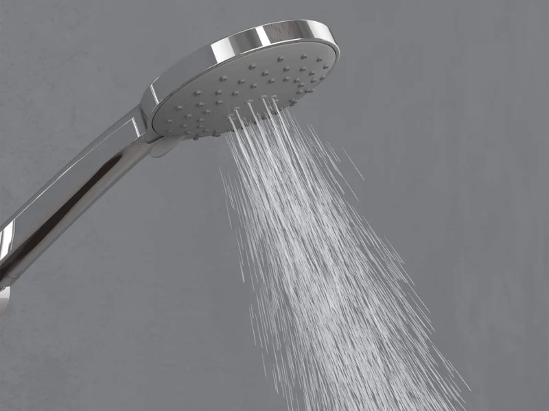 Douchette Universal Showers en mode Intensif Un pommeau de douche chromé diffusant des jets d’eau provenant des buses centrales vers le bas devant un simple fond gris.