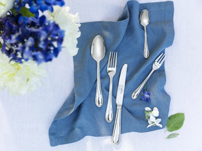 Des couverts de table Mademoiselle sur une serviette en lin bleu avec un bouquet de fleurs Une décoration de table élégante avec des couverts de table Mademoiselle sur une serviette en lin bleu et un bouquet de fleurs.
