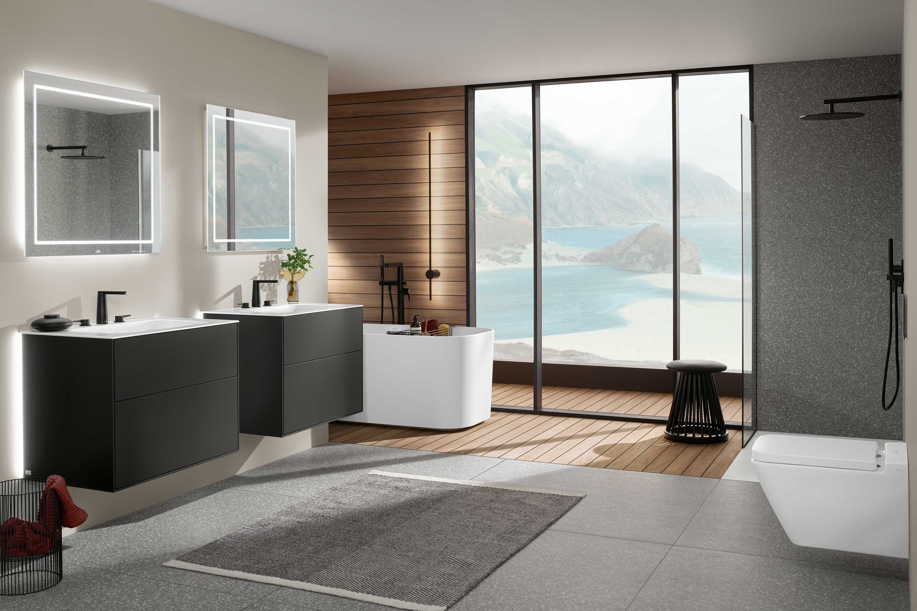 Une salle de bains Finion avec deux lavabos, deux baignoires en îlot et une douche vitrée Une salle de bains moderne avec un double lavabo suspendu Finion, des miroirs éclairés, une baignoire en îlot, une douche vitrée et de grandes fenêtres offrant une vue sur la côte. Un aménagement minimaliste avec un mélange de surfaces en bois et en pierre.