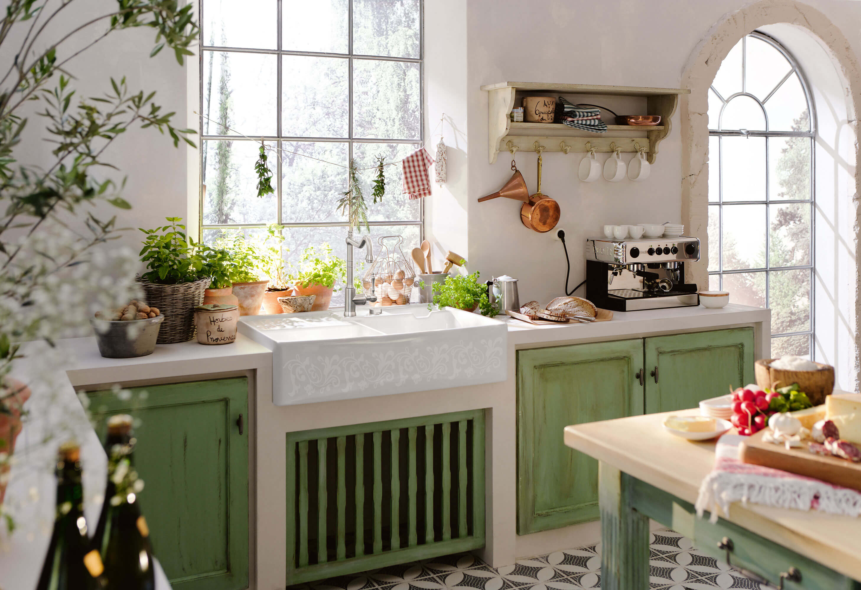 Un évier timbre d’office double dans une cuisine champêtre Un évier timbre d’office dans une cuisine champêtre avec des portes en bois vert, des ustensiles de cuisine et beaucoup d’épices et d’herbes aromatiques.