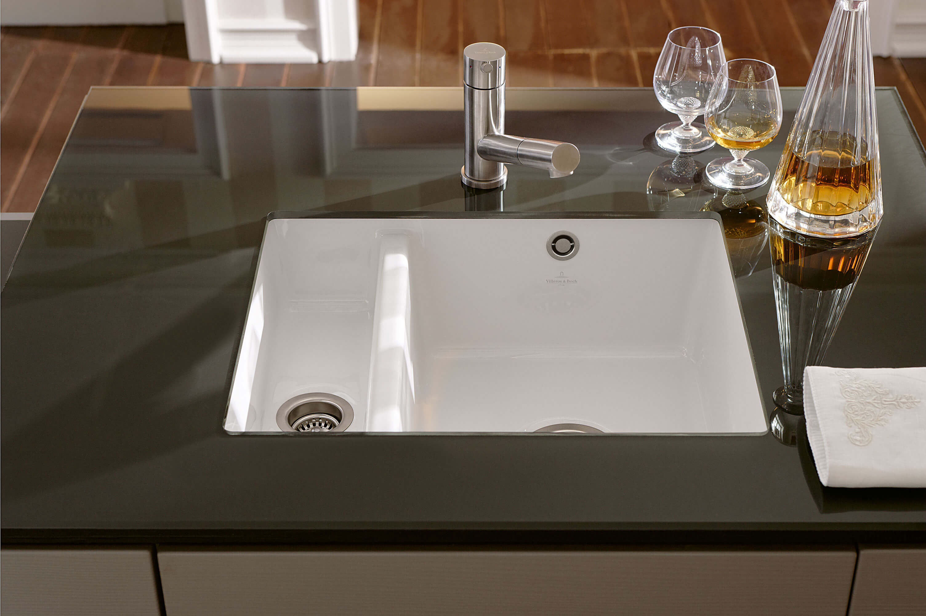 Évier de cuisine Subway blanc avec des verres Un évier de cuisine moderne avec un seul robinet, encastré dans un plan de travail noir, avec deux verres.