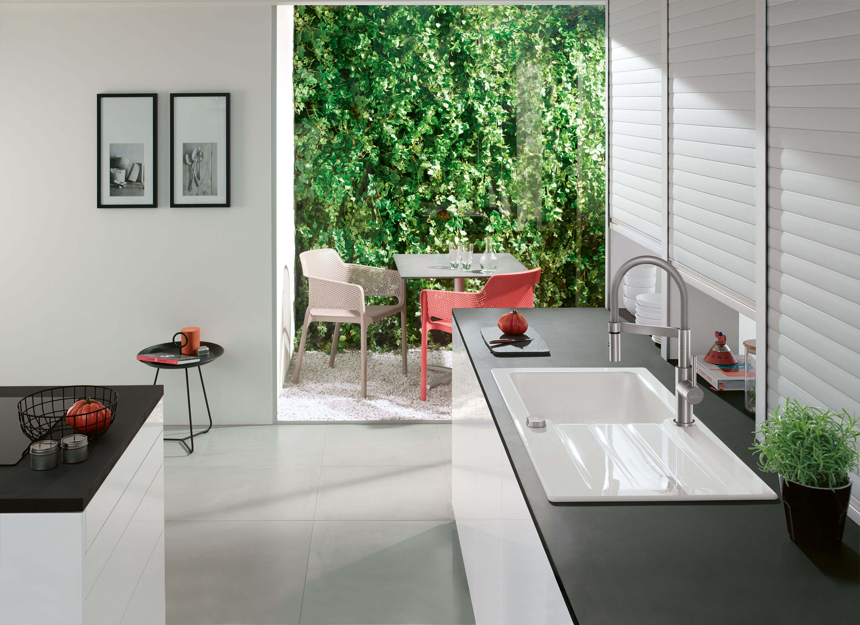 Un évier en céramique avec une robinetterie Un évier en céramique Architectura avec une robinetterie de cuisine sur un plan de travail noir avec un ensemble de tables en arrière-plan